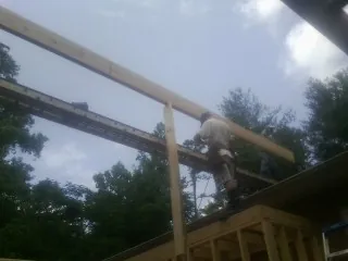 Carpenter setting a ridge beam over a new addition frame — Ice Dam Removal by Roofing Brothers in Owosso