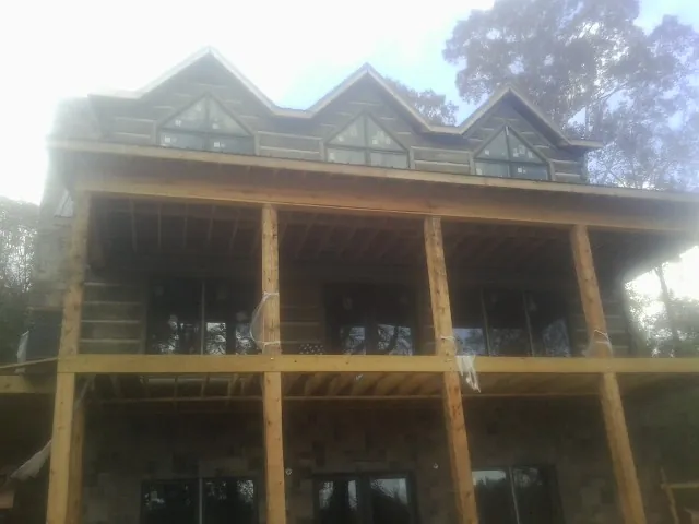 Dormers and porch framing on a large log home under construction — Roof Coating work by our crew in Owosso