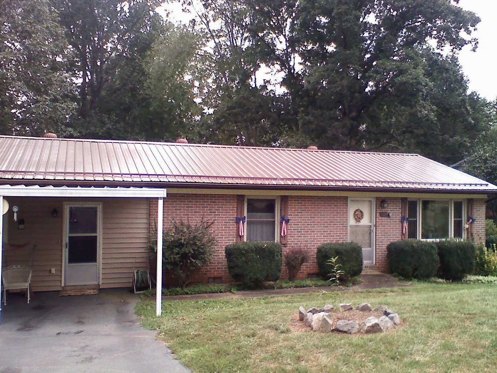 Bronze metal roof and carport on a brick ranch home — Roof Repair work by our crew in Owosso