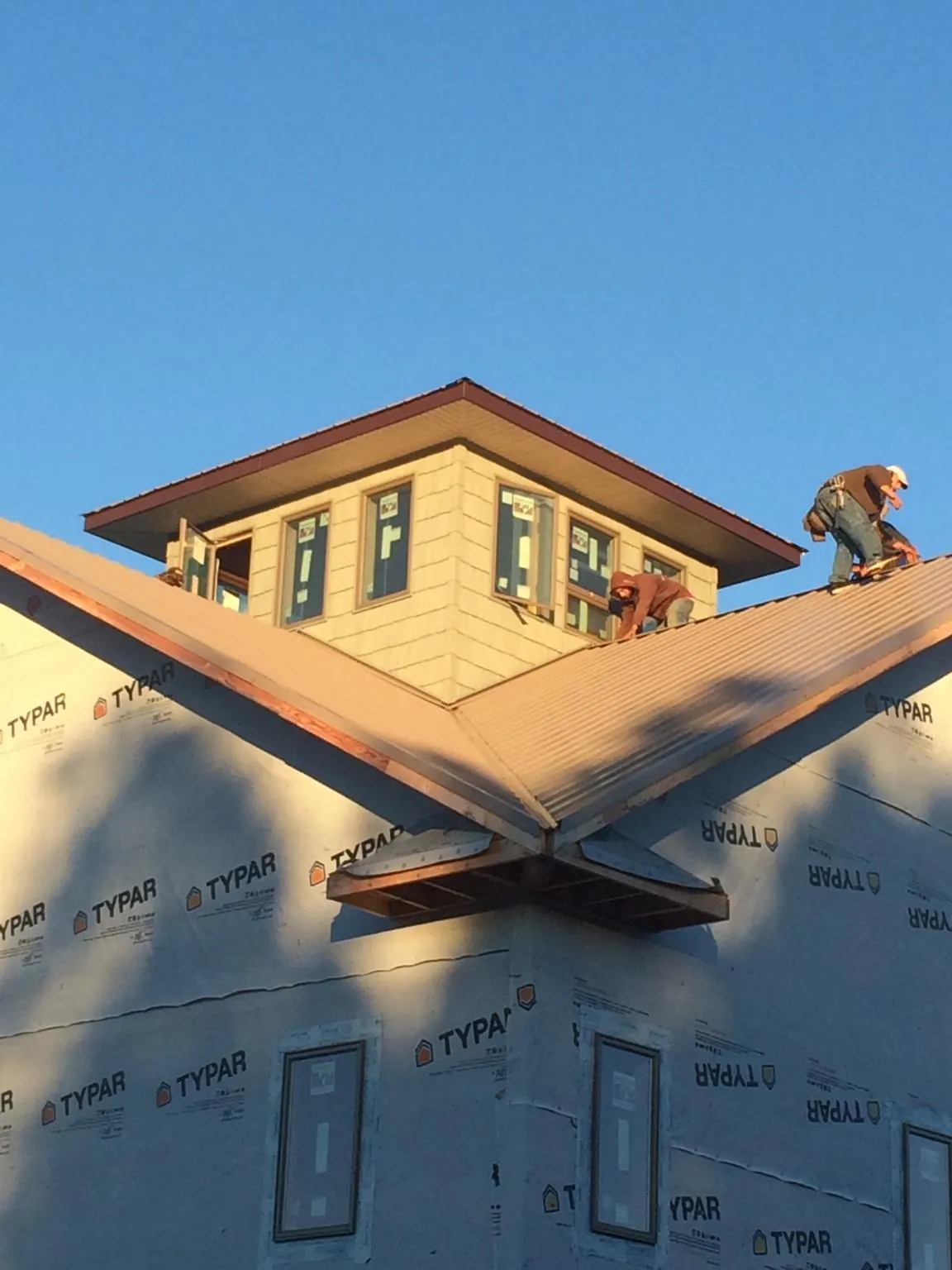 Roofers working around a rooftop cupola on a new metal roof at sunset — Roof Waterproofing in Owosso by Roofing Brothers